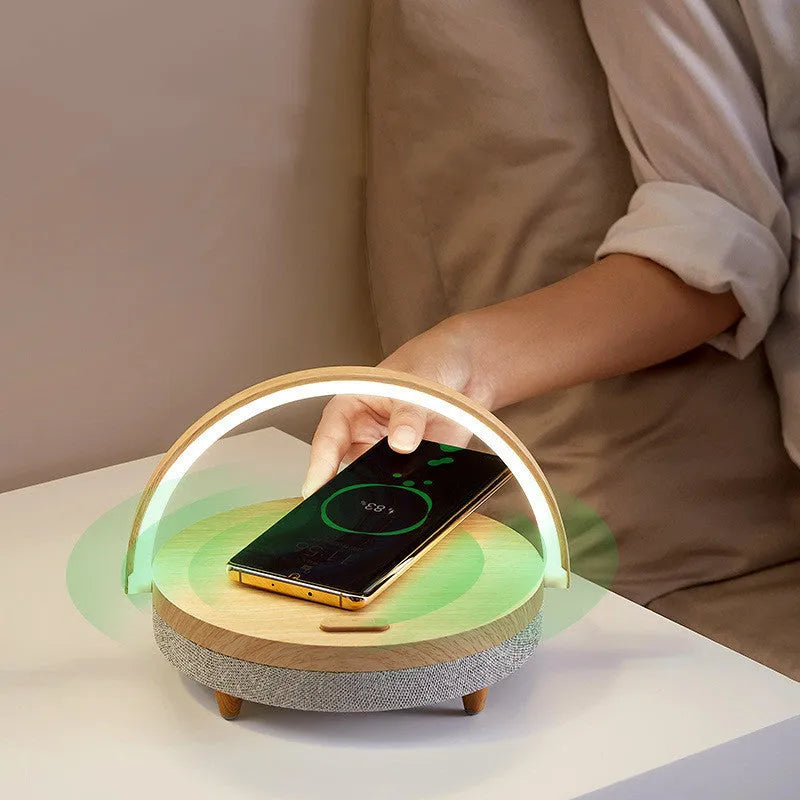 White marble-pattern wireless charging LED night light with built-in Bluetooth speaker and phone holder on wooden table.