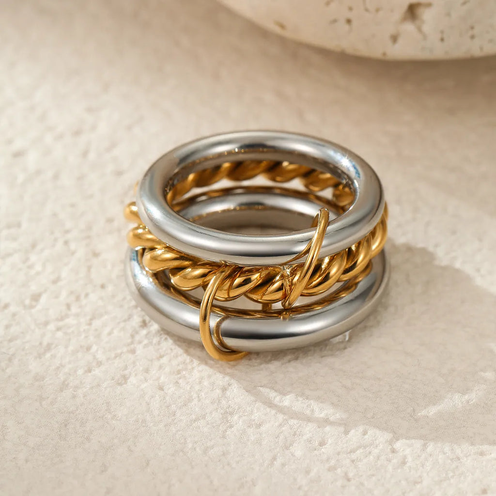 Stacked stainless steel rings with 18K gold plating in three colour variations, showing adjustable free size design