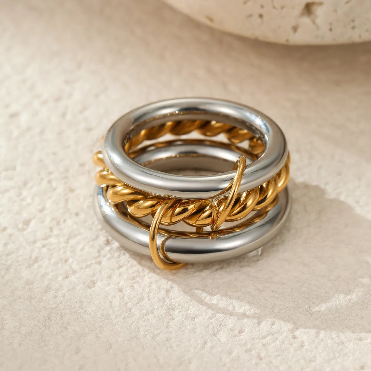 Stacked stainless steel rings with 18K gold plating in three colour variations, showing adjustable free size design