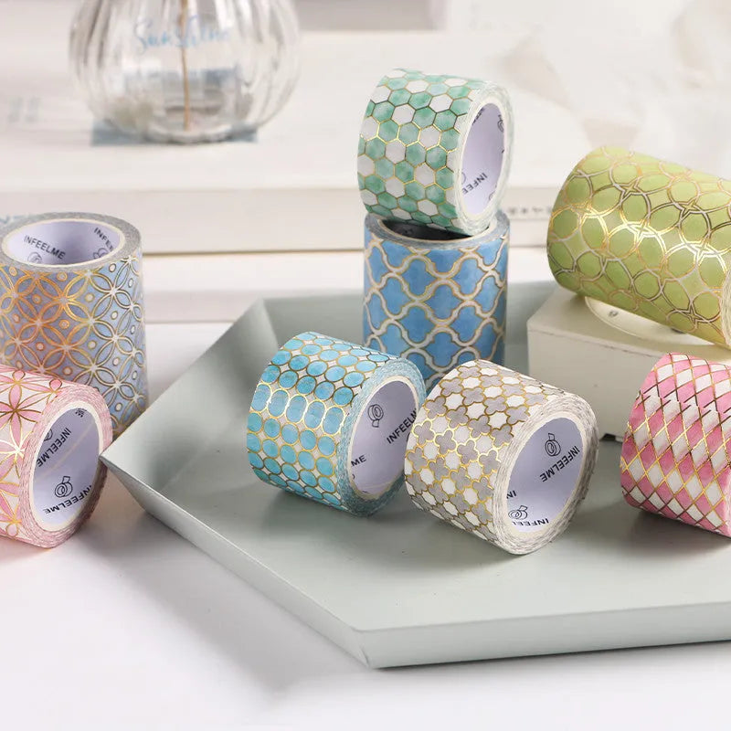 Rolls of Alice in Wonderland themed bronzing and paper tape in blue, gold, green, orange, and pink.