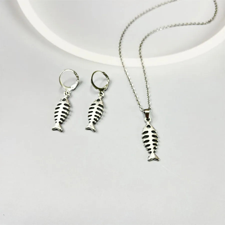 Fishbone pendant necklace with adjustable chain and matching retro earrings set on dark background