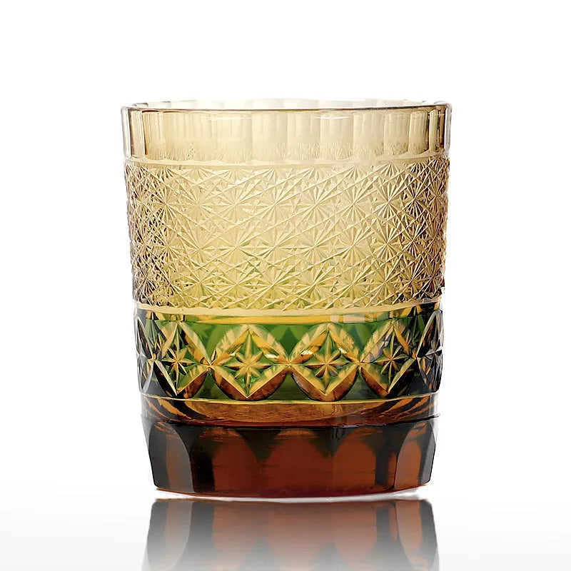 Hand carved Japanese style crystal whiskey glass in amber colour on a dark surface