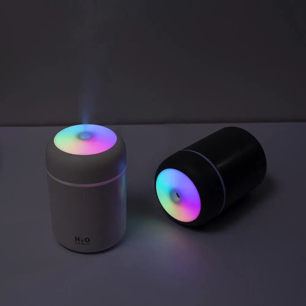 Pink USB mini humidifier with colourful lights on wooden desk