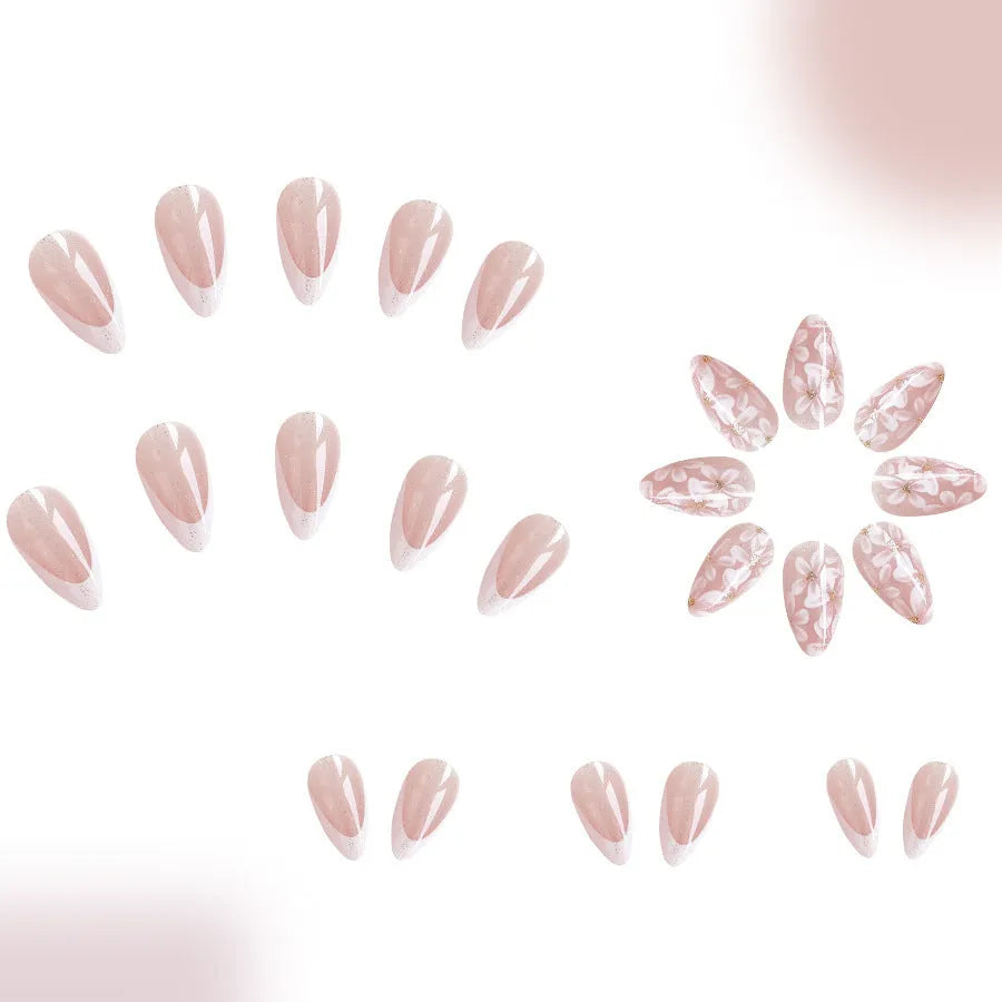 Short almond-shaped artificial nails with white French tips and glittering powder flower designs on translucent base