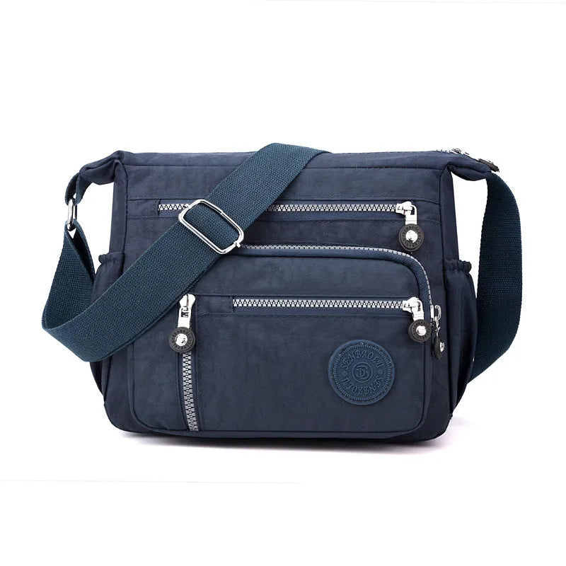 Nylon messenger bag in dark blue with single shoulder strap and soft square design, showing lining cloth interior.