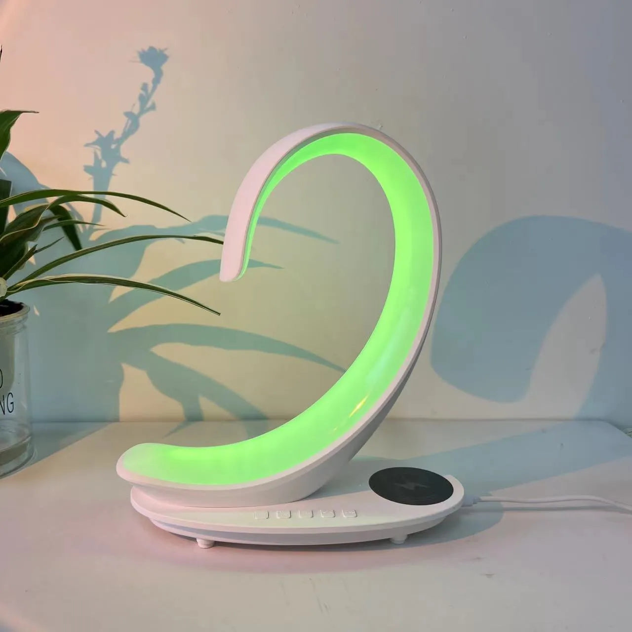 White swan shaped desktop device with colourful lighting, wireless charging pad, and Bluetooth speaker functions