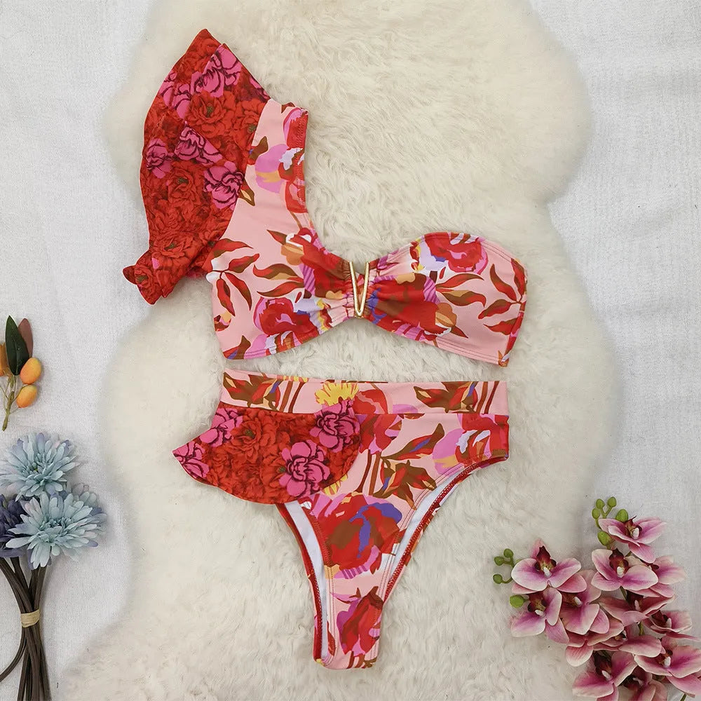 Pink women's one-shoulder ruffled bikini with red flower print and high-waist briefs.