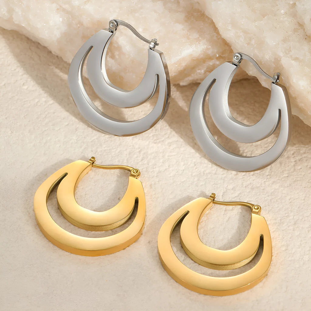 A pair of geometric minimalist French earrings in a round ring design, shown in both gold and steel metallic finishes.