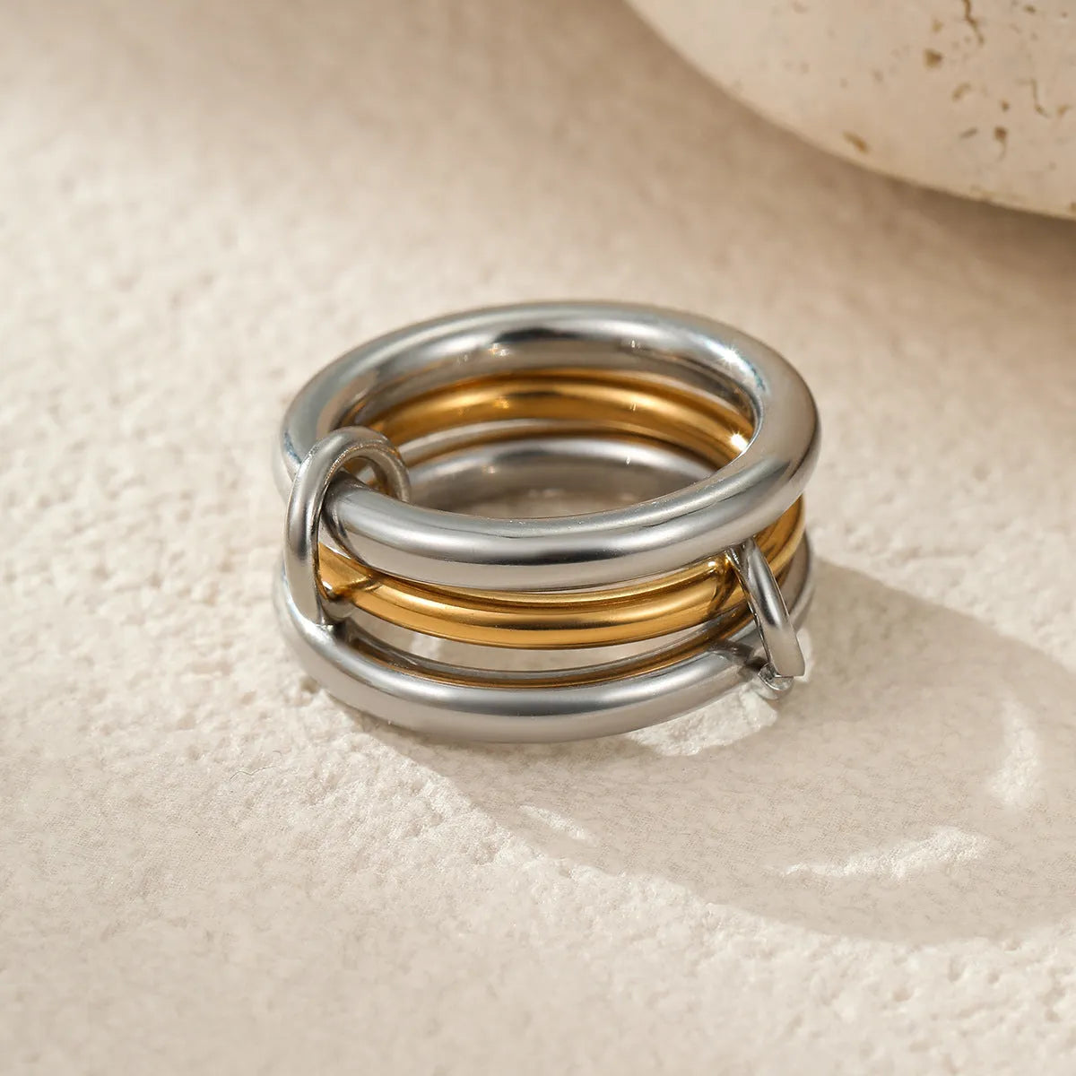 Stacked stainless steel rings with 18K gold plating in three colour variations, showing adjustable free size design