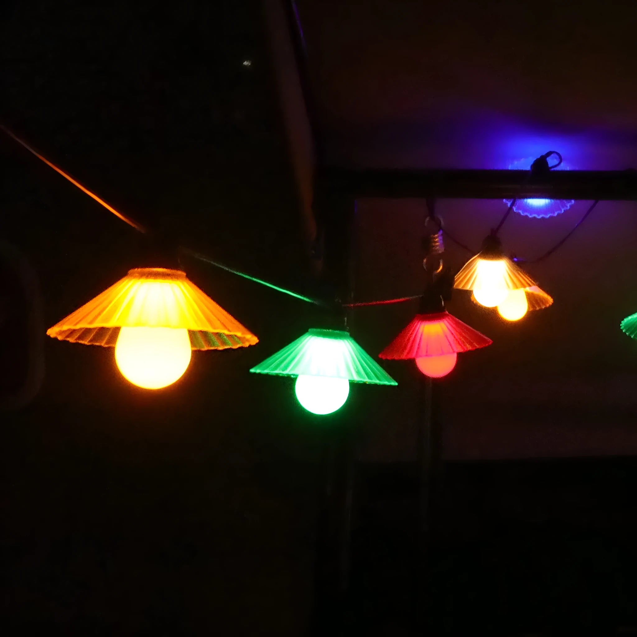 Outdoor LED string lights with white flower-shaped bulbs hanging in a garden setting.