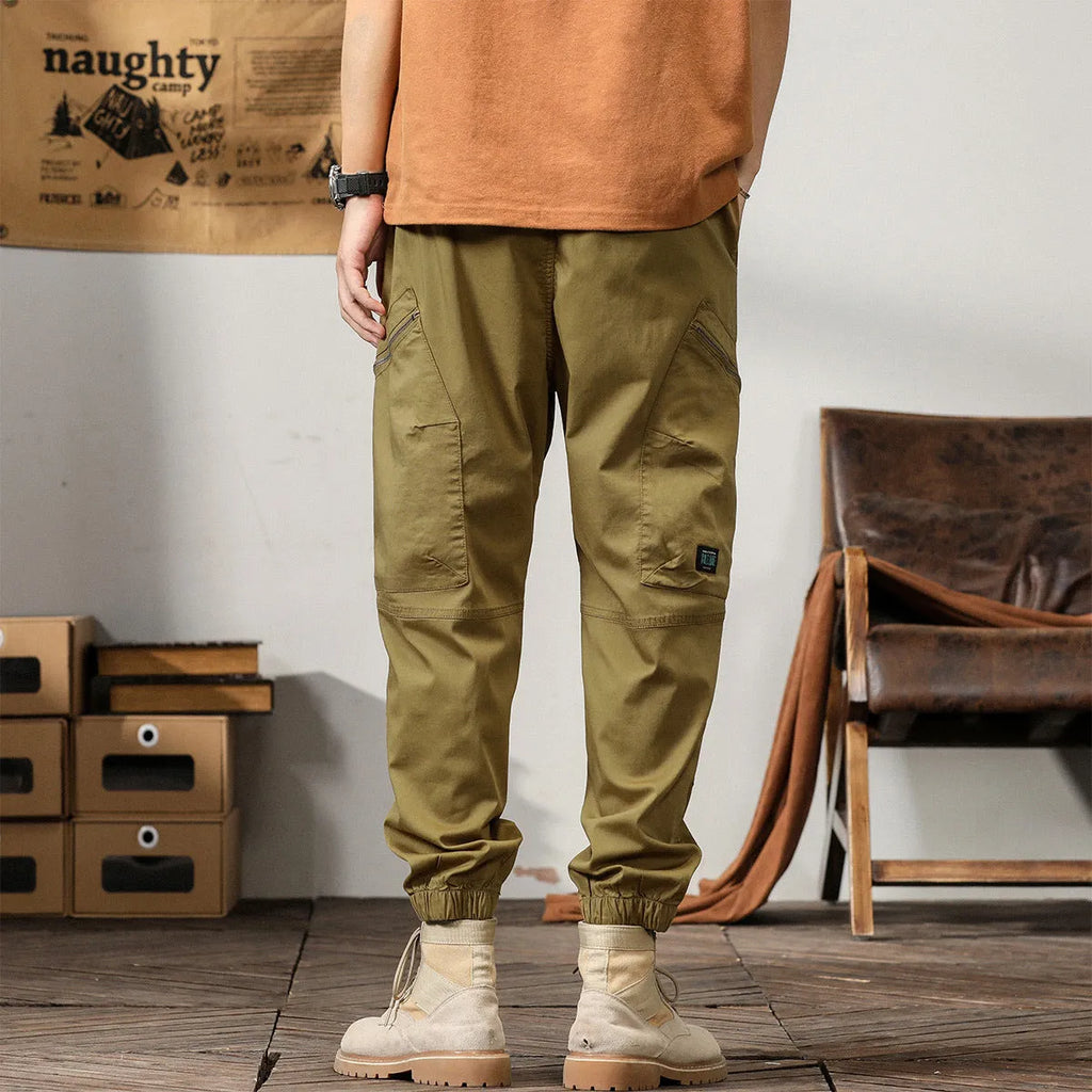 Men's khaki harem pants with tapered legs and ankle bands, made from non-iron cotton fabric.