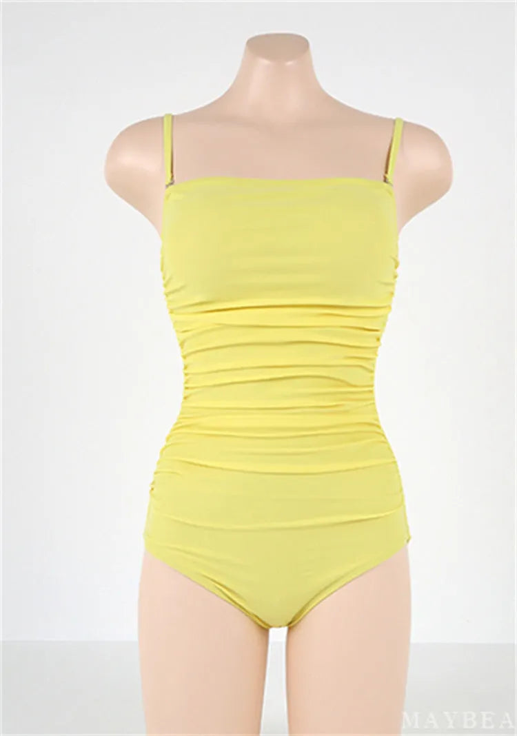 Sling style one-piece swimsuit with belly pleats in black, blue, white, or yellow on a model
