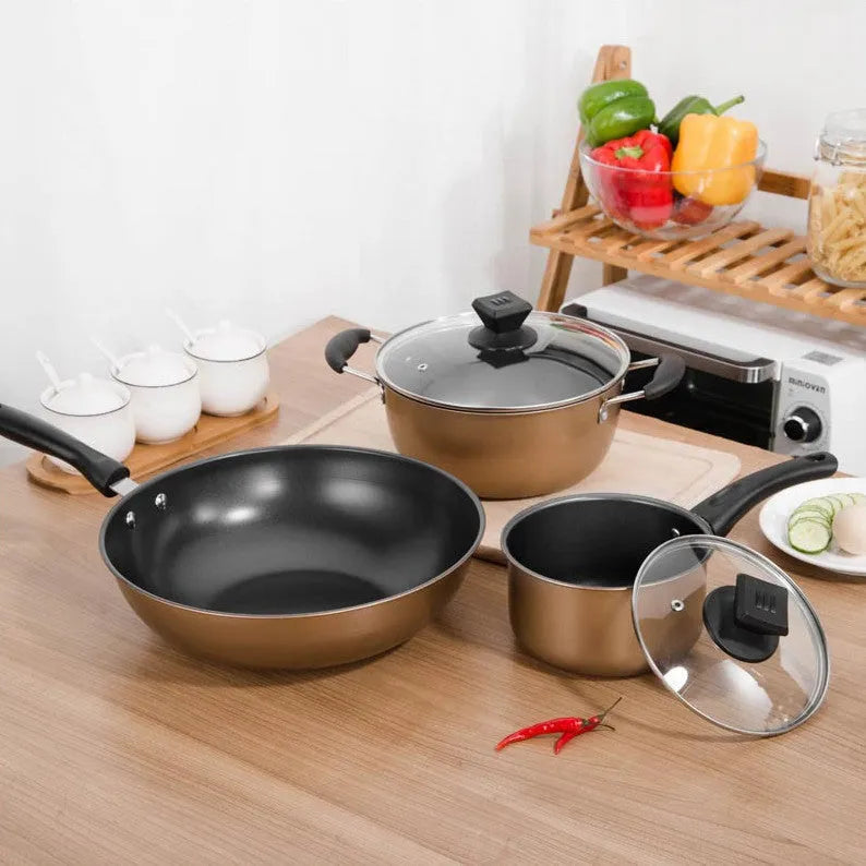 Cast iron three-piece cookware set with soup pot, milk pot, and wok on a kitchen counter