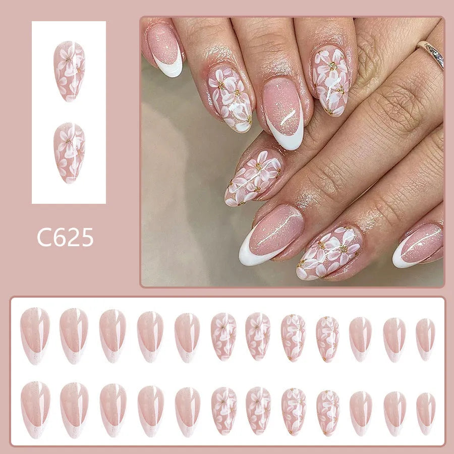 Short almond-shaped artificial nails with white French tips and glittering powder flower designs on translucent base