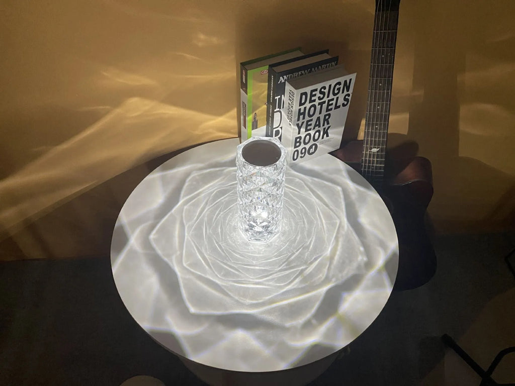 Clear acrylic rose-shaped LED table lamp with touch controls on a wooden surface.