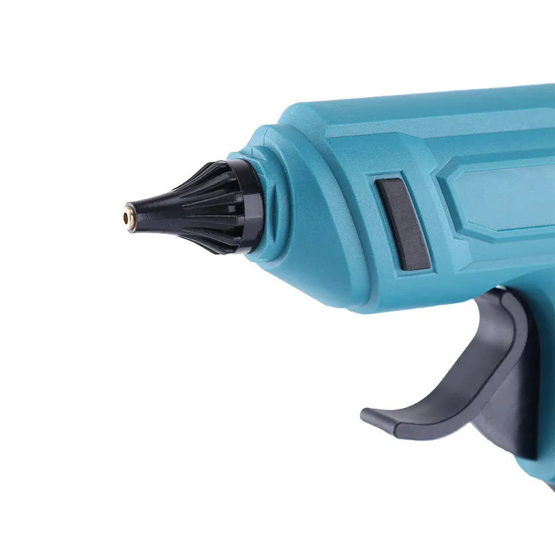 Cordless hot glue gun with two batteries, a charger, and a pack of glue sticks on a workbench.
