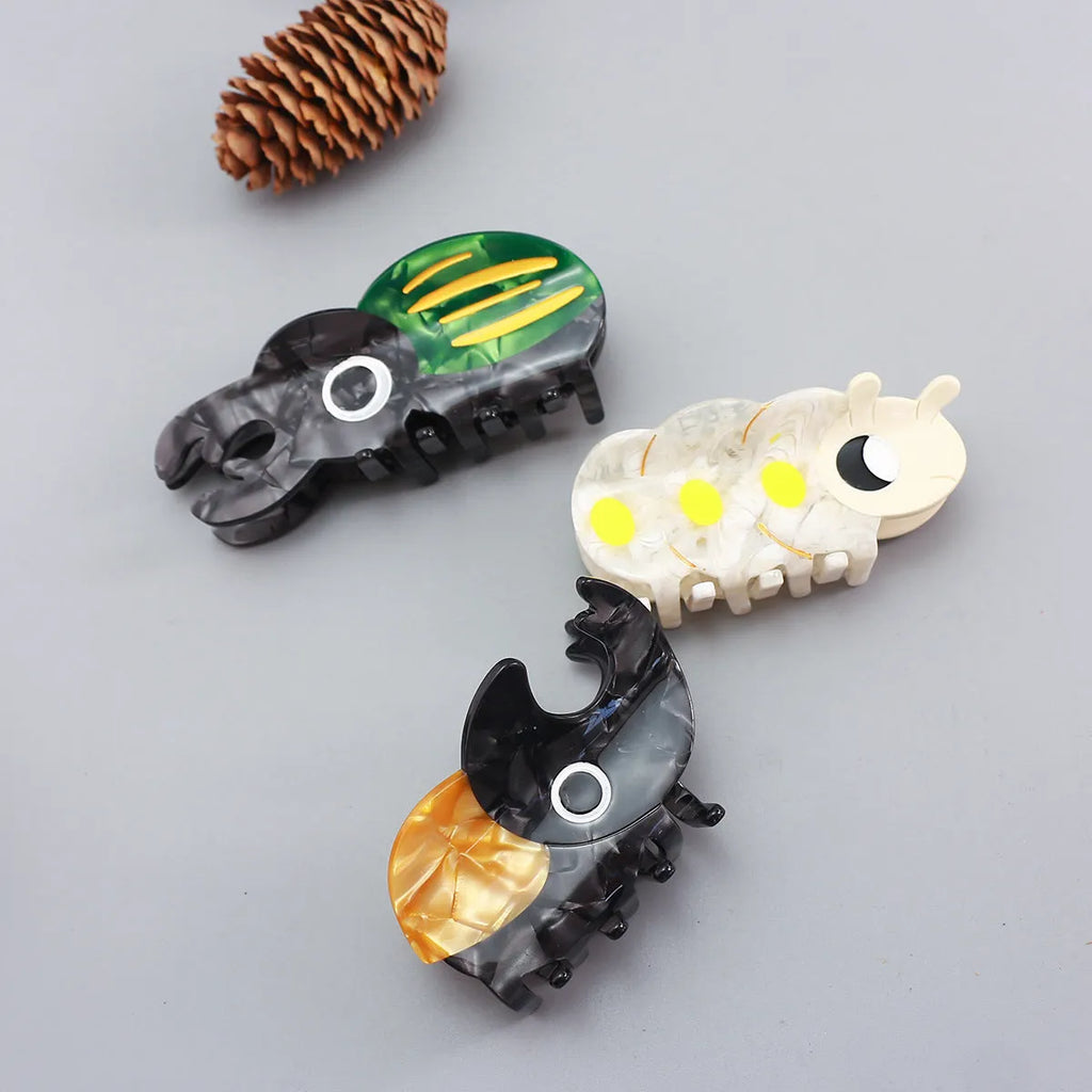 Handmade cartoon insect design hair grip in green beetle, orange beetle, or white caterpillar colour on cellulose acetate.