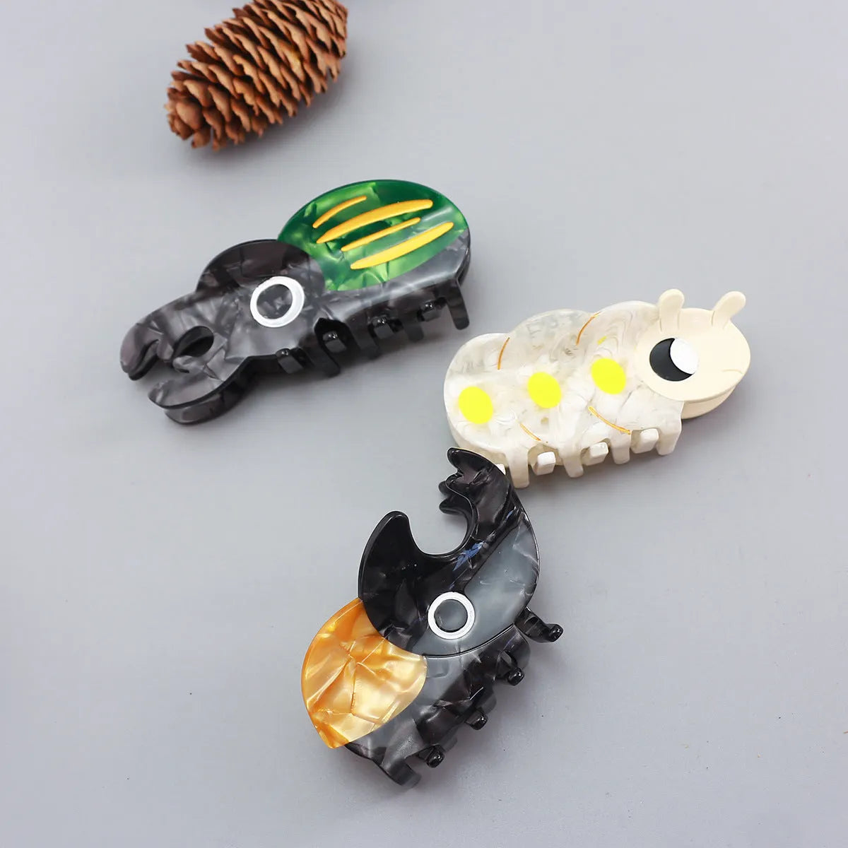 Handmade cartoon insect design hair grip in green beetle, orange beetle, or white caterpillar colour on cellulose acetate.