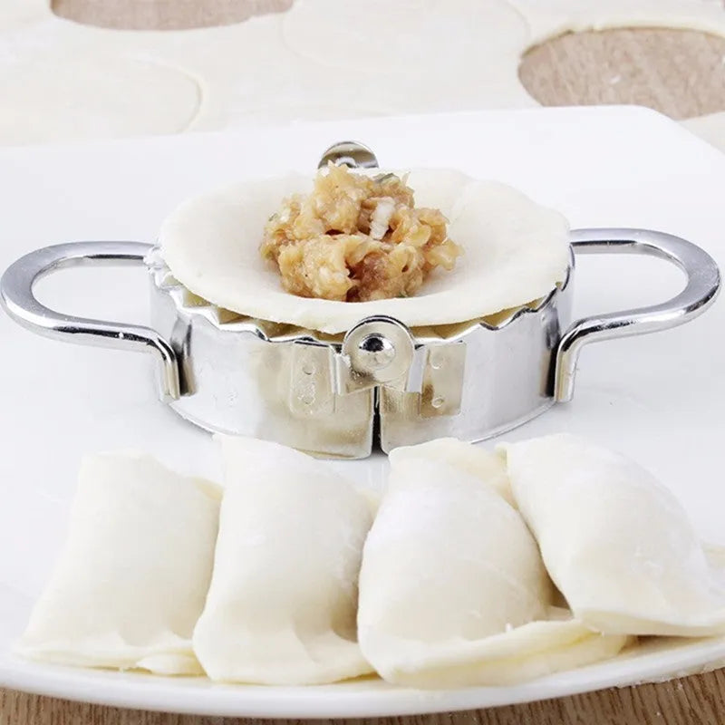 Stainless steel dumpling mould and rectangular dough cutter on a kitchen surface.