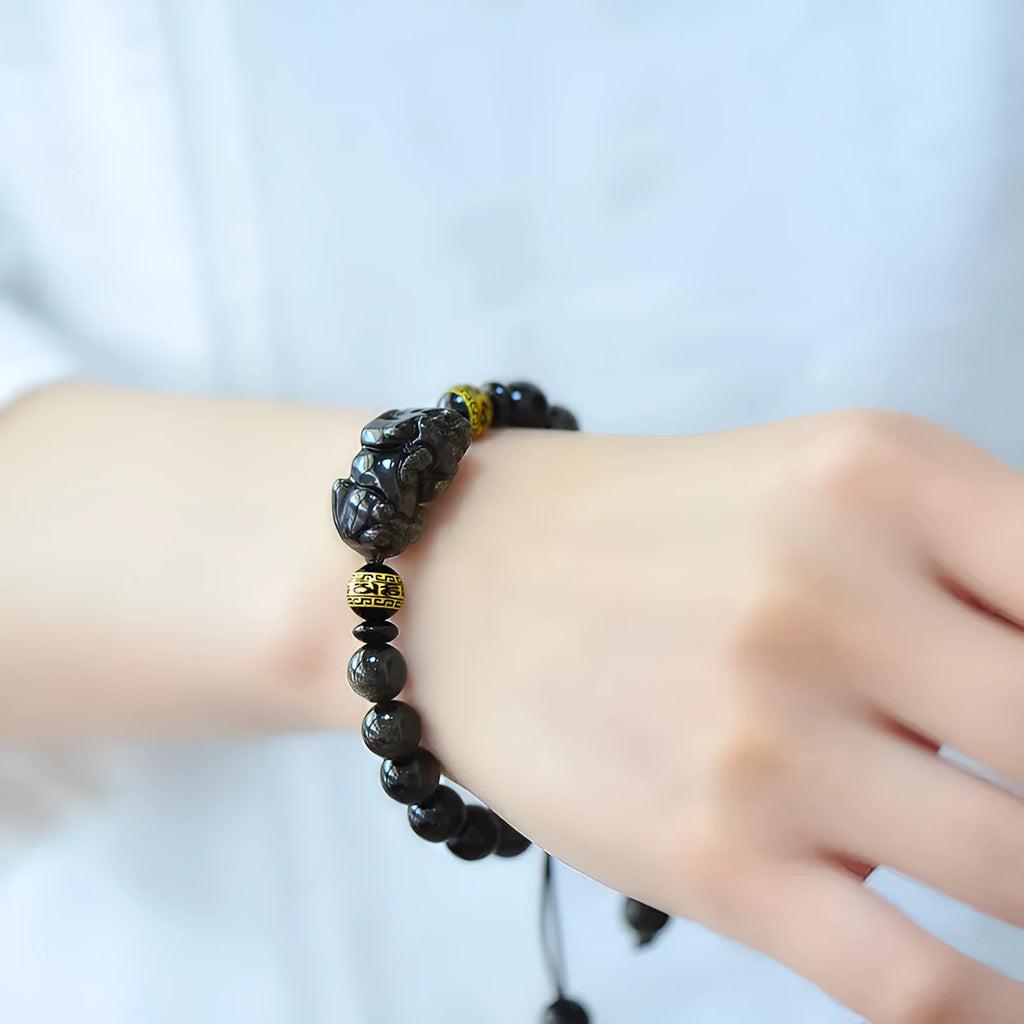 Hand-woven Golden Obsidian Pi Xiu bracelet with animal charm on wrist, showing bead detail.