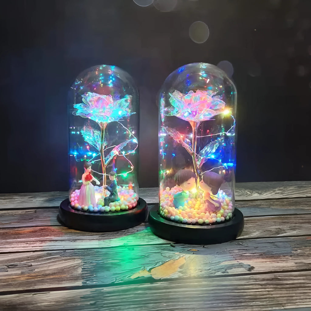 Gold artificial roses inside a clear glass dome ornament with LED lights and decorative accessories.