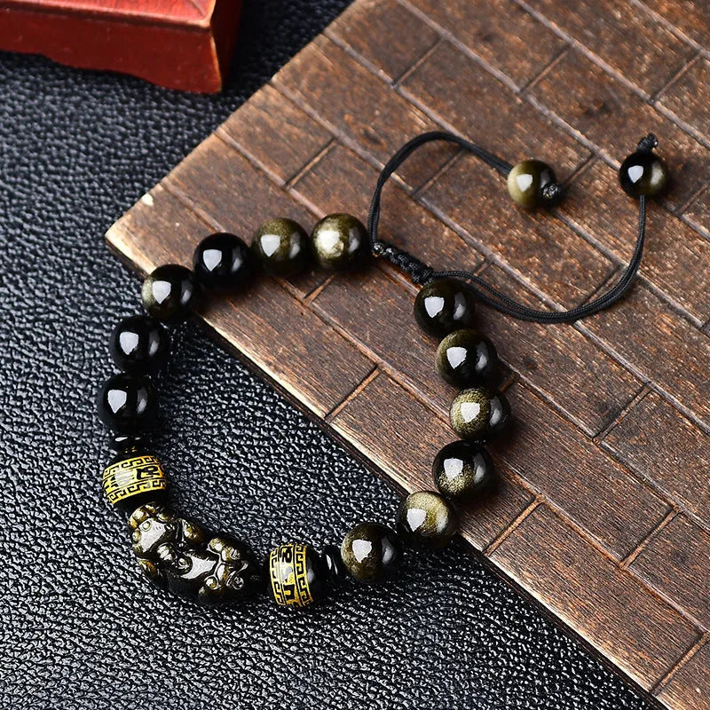 Hand-woven Golden Obsidian Pi Xiu bracelet with animal charm on wrist, showing bead detail.