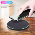 Black Quick Qi wireless charging pad for iPhone 11 on a wooden desk.