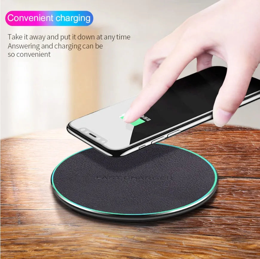 Black Quick Qi wireless charging pad for iPhone 11 on a wooden desk.