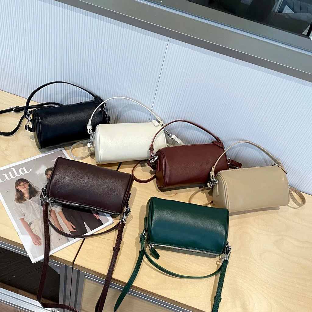 Cylindrical leather crossbody bag for mobile phones in six colours, showing visible sewing thread and compact size.