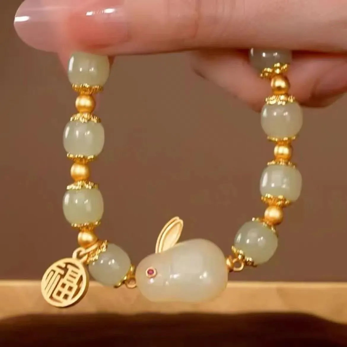 Green jade hare bracelet with black cord showing fu character charm and lily detailing
