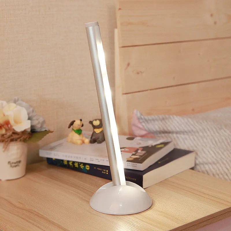 White LED portable night light with a remote control on a wooden surface.
