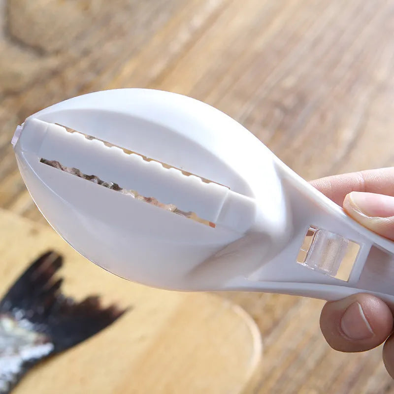White fish-shaped kitchen scaler tool with a cover and hanging hole on handle