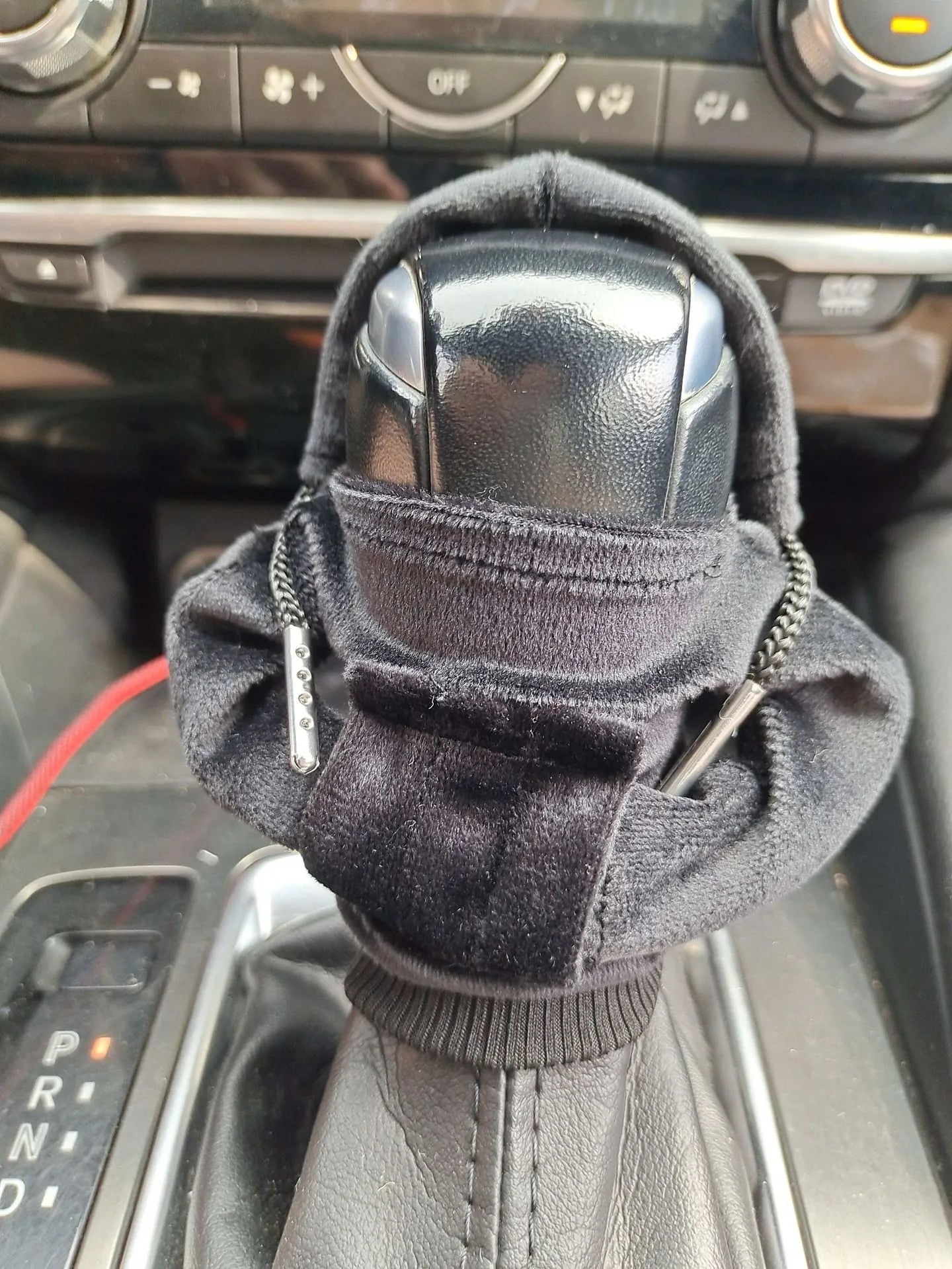 Hand-knitted red pure cotton gear lever sweater decoration on a car gear stick.