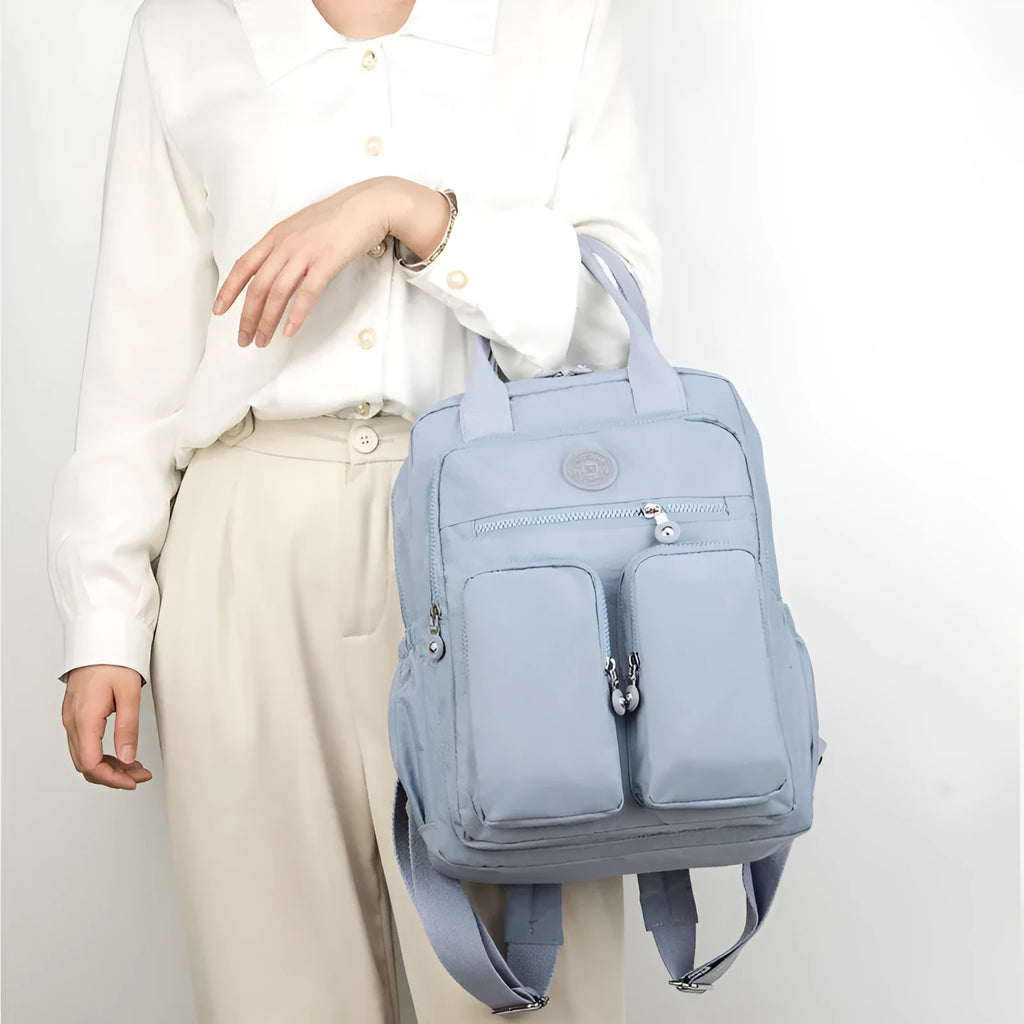 Large purple waterproof travel backpack showing front organiser pocket and internal laptop and camera compartments.