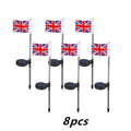 Solar-powered garden flag light with a stainless steel pole displaying a British flag design at night.