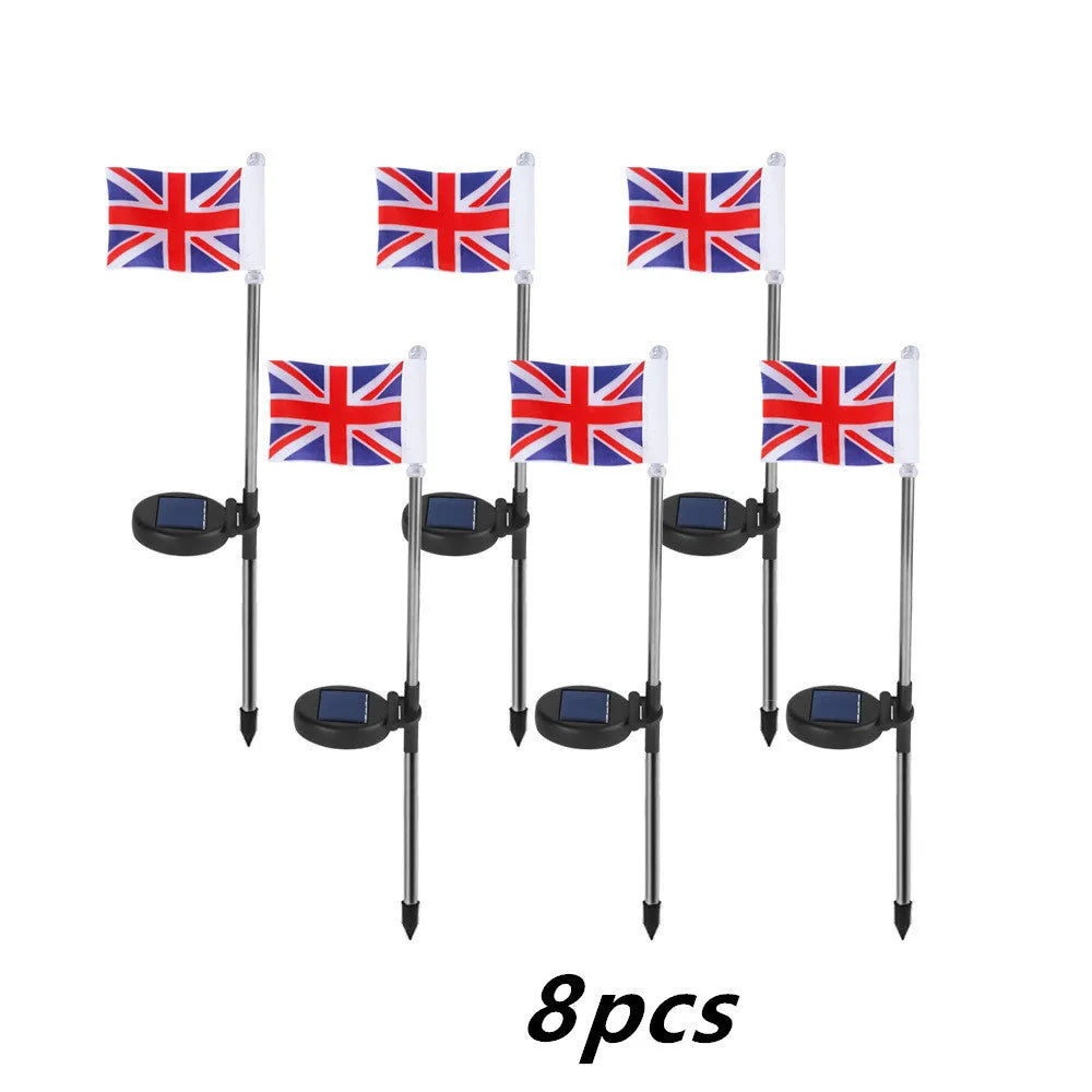 Solar-powered garden flag light with a stainless steel pole displaying a British flag design at night.