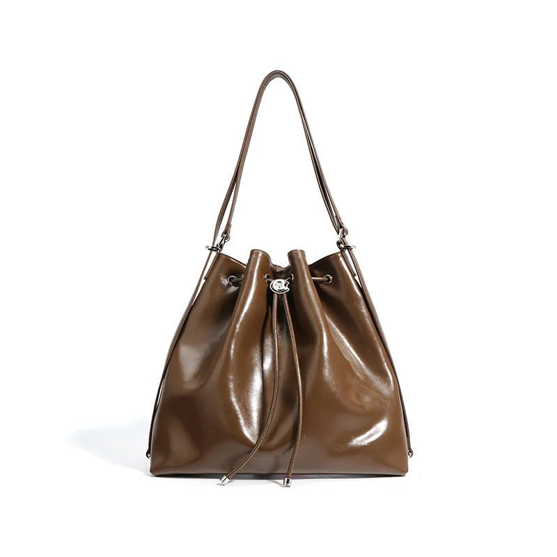 Genuine leather one-shoulder bucket bag in brown showing interior file compartment and zippered pockets