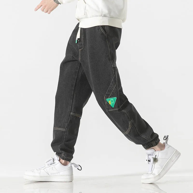 Men's loose-fit tapered trousers in 100% cotton, available in black, blue, and grey colours, showing tapered leg design.