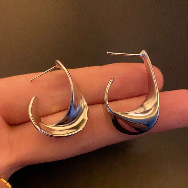 A pair of twisted geometric design metal earrings in gold or silver electroplated finish.