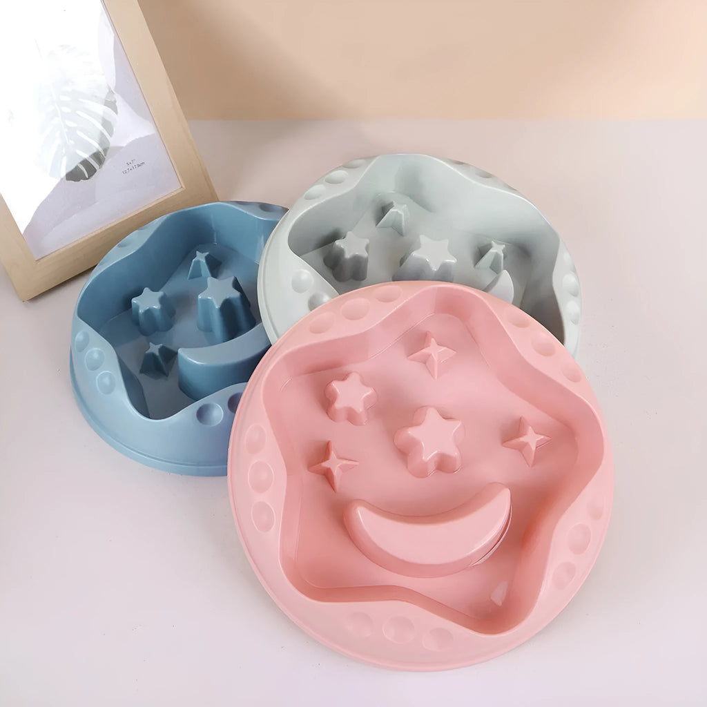 Moon star wings design slow feed dog bowl in blue, shown on a floor.