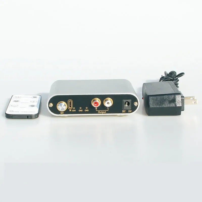 Silver aluminium alloy audio source switcher unit with front-panel switch button and infrared remote control.