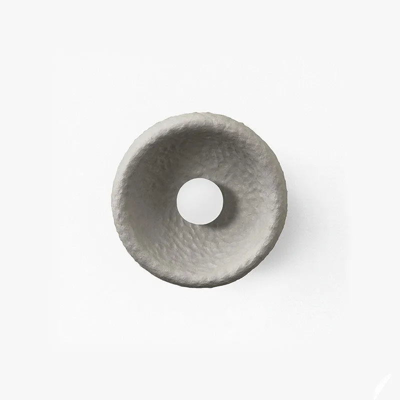 Japanese-style simple white resin wall lamp emitting warm light on a plain wall.