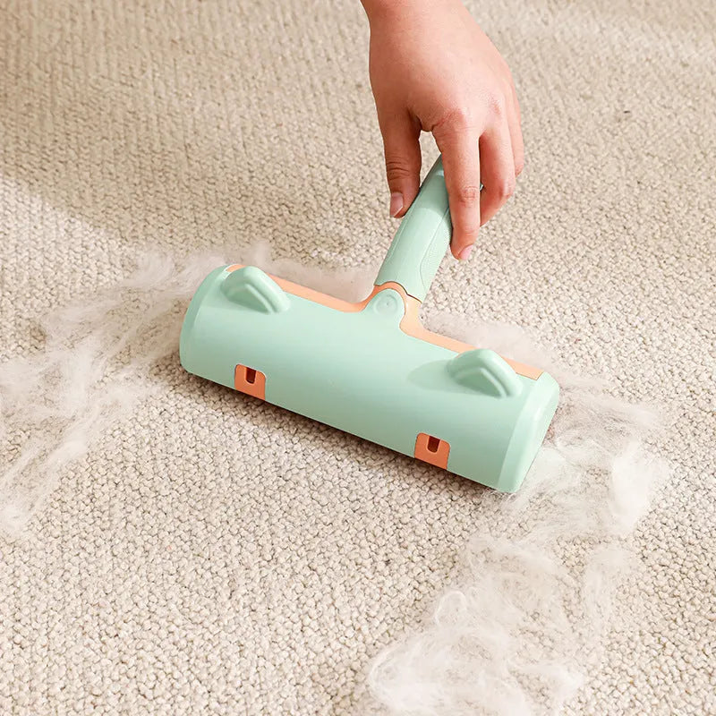 Mint green manual cat hair removal brush with detachable fur collection bin on a grey sofa