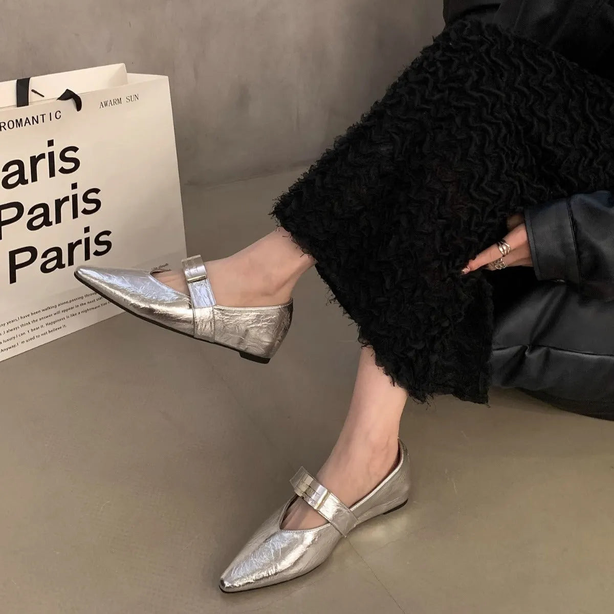 Women's black pointed toe Mary Jane shoes with a silver buckle and a low flat heel.