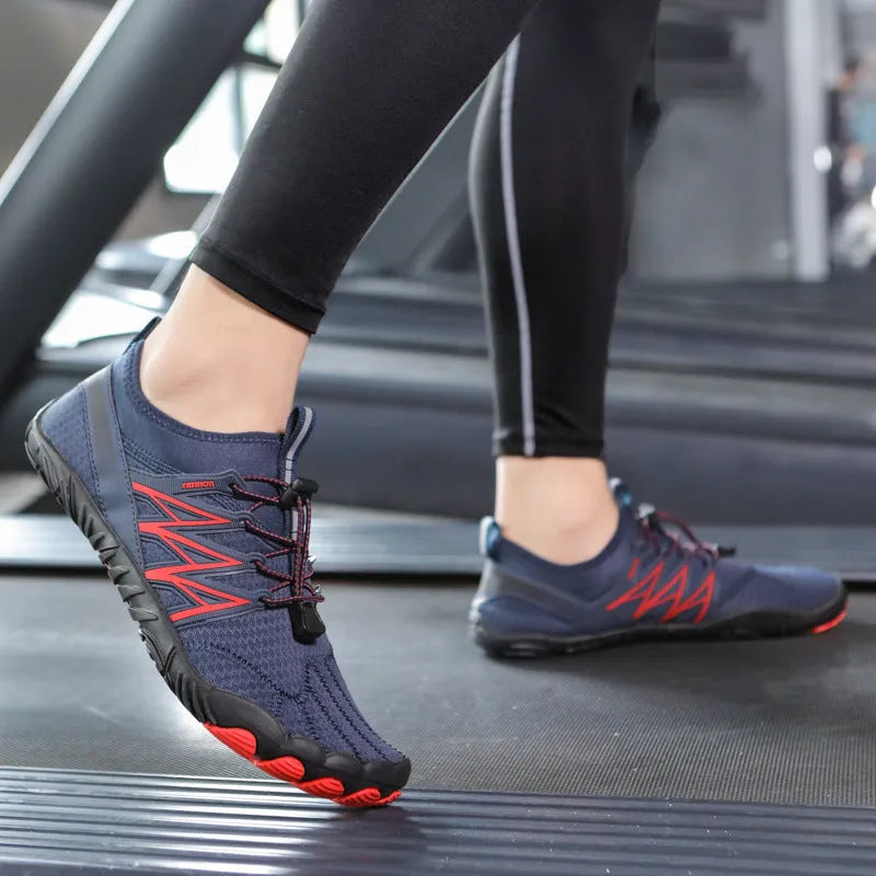 Low-top black and grey indoor training sneakers with mesh upper and rubber sole on a gym floor.