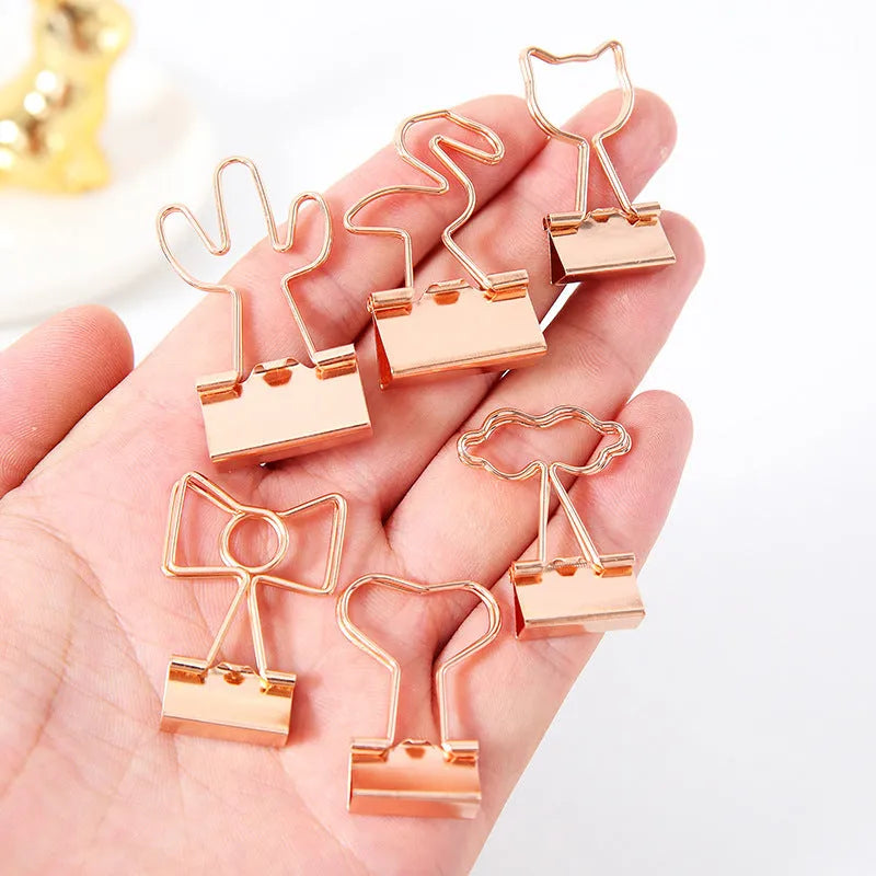 Golden alloy office clip with decorative top, 6.5cm long, holding papers on a desk