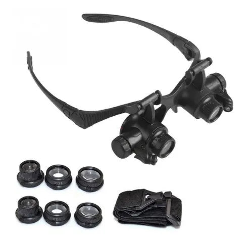 Black hands-free magnifier glasses with LED lights and four pairs of interchangeable magnification lenses on a workbench.