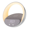 Beige multifunctional wireless charger clock with digital display, fabric speaker grille, and LED wake-up light on a wooden surface.