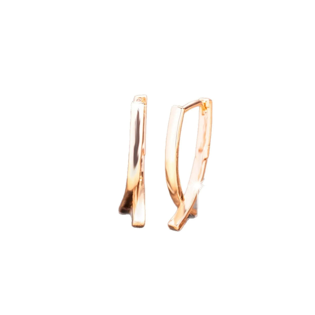 Pair of rose gold cross-shaped earrings on a plain background, showing pierced post design.