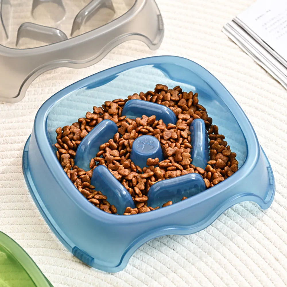 A blue plastic dog slow feeder bowl designed to prevent choking, shown alongside grey, green, and orange colour options.